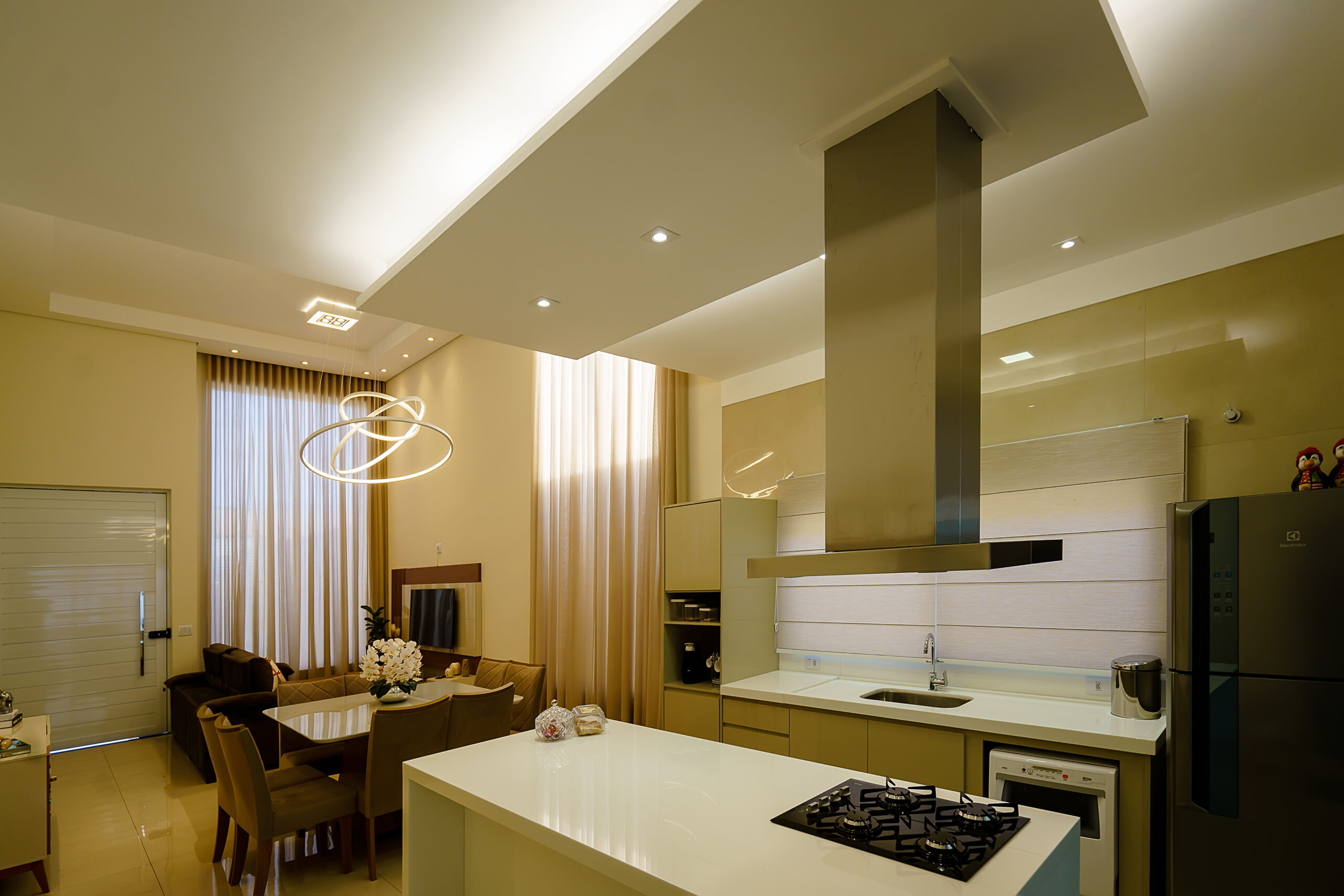 Projeto luminotécnico residencial, cozinha e sala integrados, sanca flutuante, spots e lustre de arcos sob a mesa de jantar
